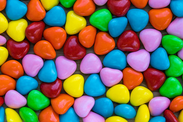 Background in the form of hearts made of milk chocolate, coated with multi-colored glaze, top view