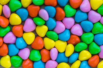 Background in the form of hearts made of milk chocolate, coated with multi-colored glaze, top view