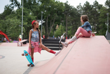 Two female skaters best friends hangout at the skate park on sunset .Laughing and fun.