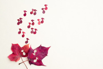 Red notes shoot out of two maple hearts. The concept of autumn sad music