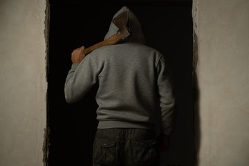 A hooded man with an axe on his shoulder rear view