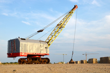 Large crawler crane or dragline excavator with a heavy metal wrecking ball on a steel cable....