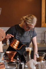 Professional barista preparing coffee using chemex pour over coffee maker and drip kettle. Young woman making coffee. Alternative ways of brewing coffee. Coffee shop concept. - obrazy, fototapety, plakaty