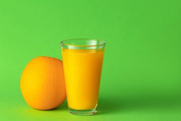 Glass of fresh orange juice on color background