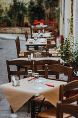 A table with glasses, white tablecloth and napkins in a street caffe. Selective focus.