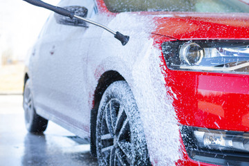 Car cleaning. Wash red car with soap. High pressure water washing