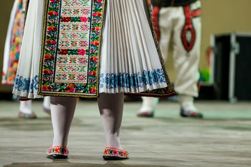 Close up of legs of young Romanian female dancer in traditional folkloric costume. Folklore of Romania