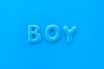 Boy word as decoration for baby shower on blue background top view