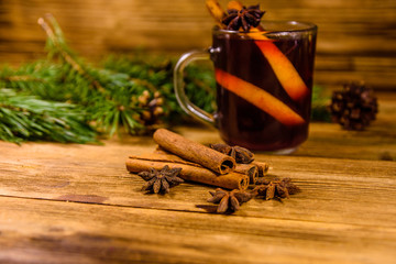 Cup of mulled wine with cinnamon and fir tree branches on wooden table