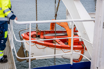Sailor standing above a lifeboat on deck of the ferry Stena Nautica