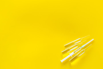 Flu vaccination. Ampoule and syringe on yellow background top view space for text