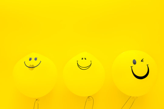 Happiness emotion. Yellow balloon with smile on yellow background top view space for text