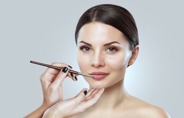 Fototapeta premium The make-up artist paints the lips of a beautiful woman, completes the make-up in the beauty salon. Professional skin care.