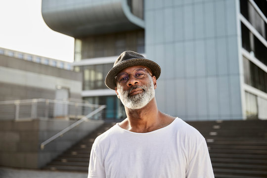 Portrait of smiling mature man with grey beard wearing hat in summer