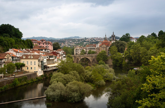 Bridge over river canal by buildings in town at Duoro Valley against cloudy sky