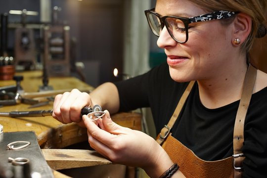 Goldsmith in workshop working on heart-shaped piece of jewelry