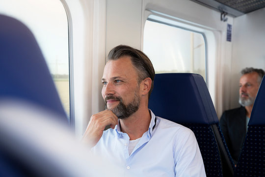 Mature man sitting in a train, looking out of window