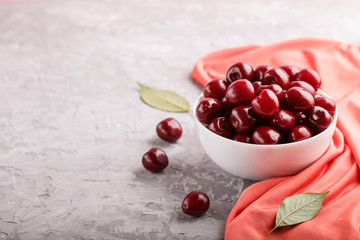 Fresh red sweet cherry in white bowl on gray and pink background. side view.