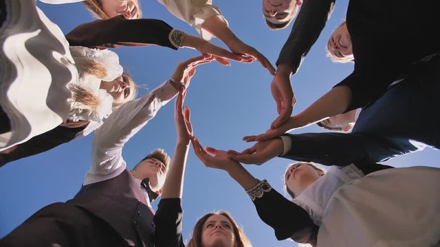 A group of graduate students make a circle from the palms of their hands.