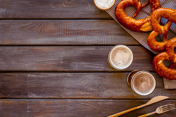 Octoberfest table background. Pretzels and beer glasses on dark wooden background top view frame copy space