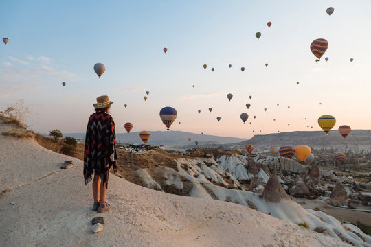 Young woman and hot air balloons in the evening, Goreme, Cappadocia, Turkey