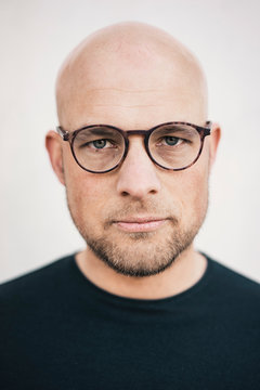Portrait of serious bald man with beard wearing glasses