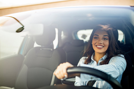 Beautiful young happy smiling woman driving her new car at sunset. Woman in car. Close up portrait of pleasant looking female with glad positive expression, woman in casual wear  driving a car