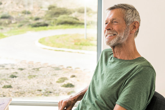 Smiling senior man sitting at the window at home