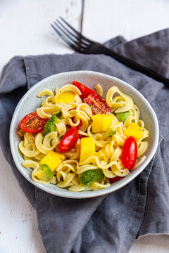 Bowl of pasta salad with mango, avocado and cherry tomatoes