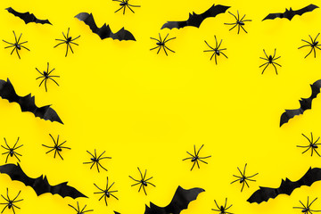 Obraz premium Stylish Halloween design. Bats and spiders on yellow background top view copy space frame