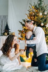Happy parents with their little son having fun on christmas decoration background