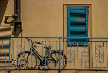 vélo rangé sur un balcon devant un volet vert fermé
