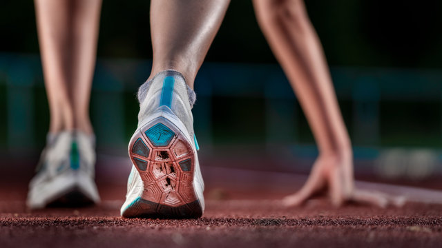 Legs of female, athlete running on tartan track