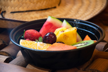 Variety colored fresh fruits cutted into the black bowl.