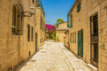 Fototapeta premium Jerusalem old city street empty passage between stone buildings in summer colorful day time 