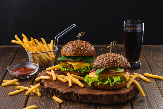 Vegetarian Burger with fries and drink on wooden table