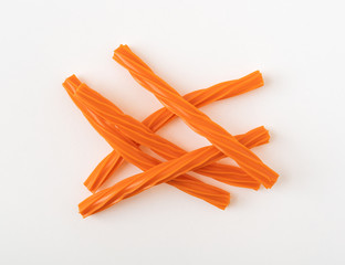 Several pieces of orange licorice on a white background.