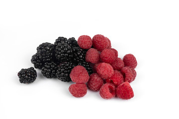 Side view on a pile of red raspberries and black shiny blackberries