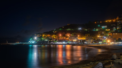 Fototapeta na wymiar Recco, Genoa, Italy. Wide view of the city of the Ligurian Riviera at night. In the foreground the reflections of the lights of the city on the sea.