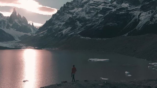 Aerial panoramic footage of female hiker witnessing breathtaking view of laguna on the Cerro Torre trek, showcasing the beautiful Patagonia mountain landscape