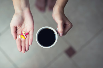 coffee mug and palm with multi-colored tablets, top view, tinted