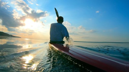 Backside view of a male boater navigating a canoe