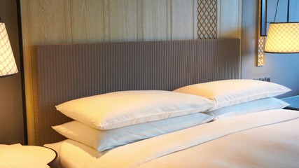 Freshly made up bed whit clean, white sheets and pillows in hotel room. Tilt down.