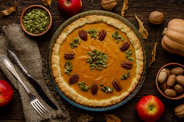 homemade pumpkin pie , pumpkin seeds and autumn leaves on a wooden background