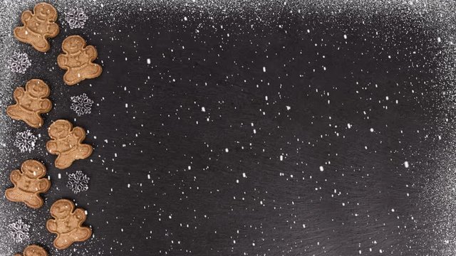 Gingerbread cookies on a slate in background and falling snow in decoration.