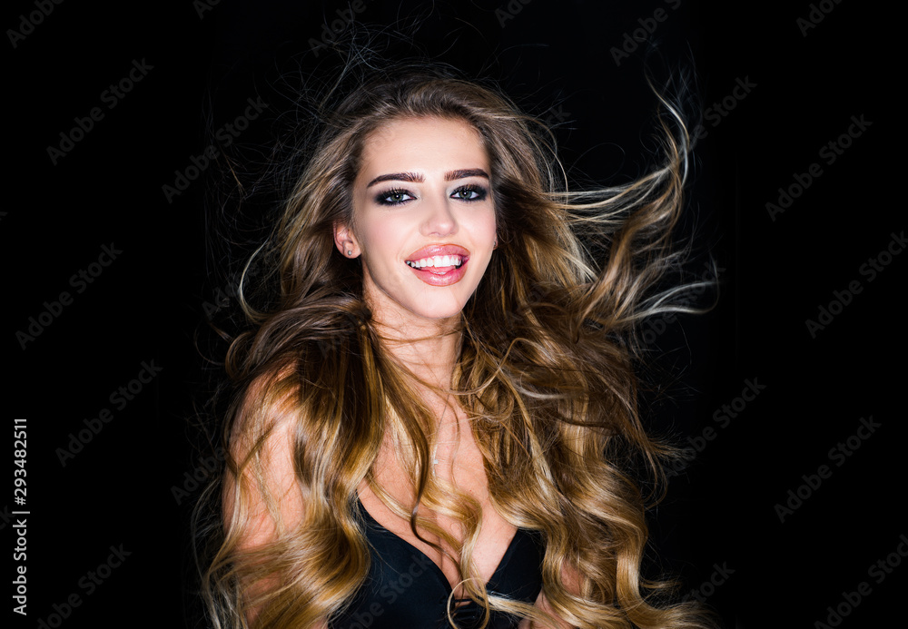 Wall mural Studio fashion shot. Beautiful cheerful and enjoying woman. Blonde woman with curly beautiful hair smiling on black background.