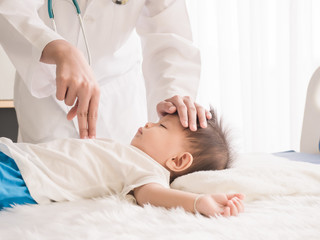 Doctor use two fingers press down on the chest of child to demonstrate CPR procedures. Demonstration of child rescuers on the bed.