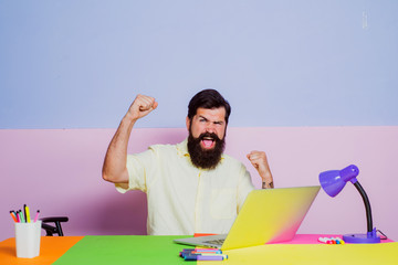 Excited man looking at laptop screen surprised by good online news. Happy male workers having fun chatting at office desk meeting.