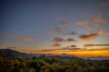 Scattered orange and purple clouds at sunset over mountain peaks