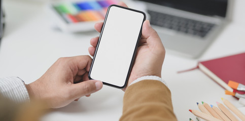 Close-up view of businessman holding blank screen smartphone in minimal workplace